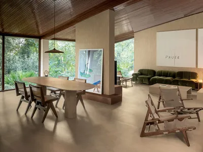 現代開放式客餐廳，設有大型木製餐桌與藤編椅、洞石地板、木質天花板、綠色絲絨沙發，以及可眺望茂密森林花園的落地窗。