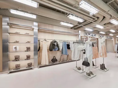 Bershka 服裝店內部，展示白色模特兒、服裝吊架、陳列靴子的木質層架、裸露天花板管線，以及印有品牌標誌的大型不鏽鋼牆面。