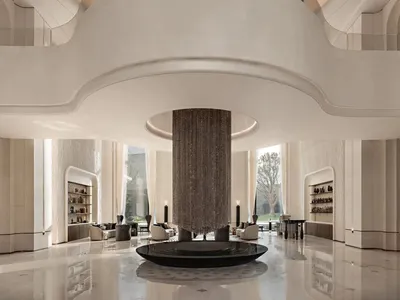 Luxurious modern hotel lobby featuring an enormous sculptural crystal chandelier hanging from a circular ceiling opening, with polished marble floors and minimalist white architectural details.