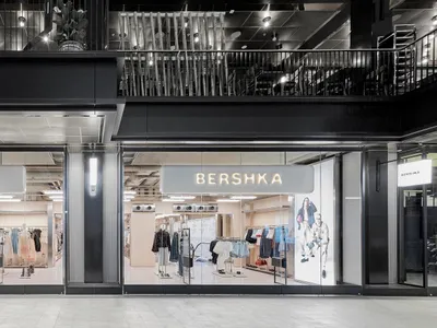 現代Bershka零售店，採用全高玻璃立面、黑色金屬框架與發光招牌，位於當代購物中心。