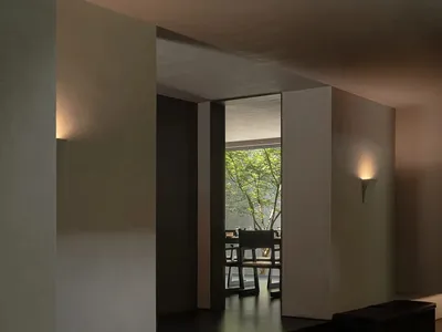 現代極簡風格室內空間，深色混凝土閱讀角落配有嵌入式黑色皮革長椅、翻開的書本，以及透過大開口望向鬱鬱蔥蔥庭園的景觀。