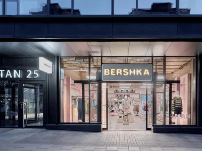 Bershka 現代服飾店夜景，大面積玻璃櫥窗內透出粉色燈光，可見服裝展示與模特兒，以及明亮的品牌招牌。
