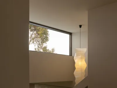 現代極簡樓梯視角，淺色橡木踏板與立板，下方有大窗與大理石壁龕，角落懸掛高挑的白色雕塑感紙質吊燈。