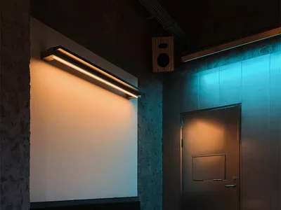 Modern industrial private dining area featuring a built-in upholstered booth, concrete walls, a rectangular dining table, round stools, and dramatic dual-tone lighting with warm white and cool blue hues.