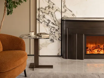 Modern living room featuring a large Calacatta marble feature wall, dark metal fireplace with burning fire, burnt orange bouclé armchair, marble side table, and a tall potted tree.