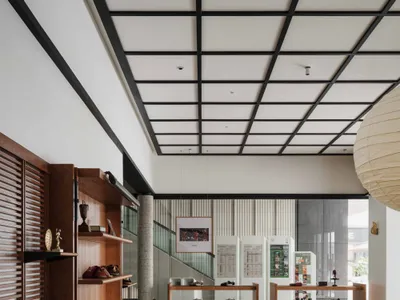Modern minimalist shoe store interior featuring walnut wood display shelves, blue cushion seating on a wooden platform, tatami-style rug, large paper lantern, and black grid ceiling.
