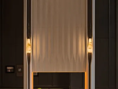 Modern luxury lobby featuring a tall sculptural travertine fireplace with linear gas fire, flanked by onyx pendant lights and dark wood paneling.