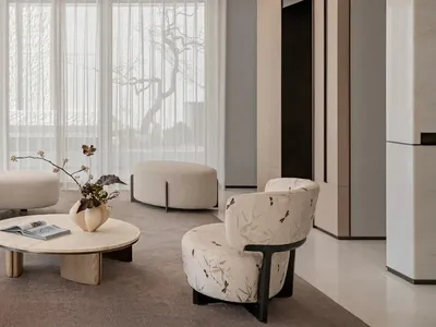 Modern minimalist living room featuring a large cream boucle curved sectional sofa, matching floral accent armchair, round light-wood coffee table, and sheer white curtains allowing abundant natural light.