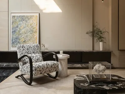 Modern minimalist living room featuring a black and white patterned rocking armchair, marble coffee table, abstract artwork, and dramatic diagonal sunlight on beige paneled walls.
