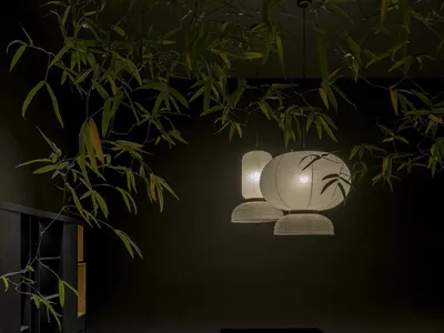 現代日式茶室，設有深色木質長桌、淺色布面扶手椅、懸掛紙燈籠，以及從天花板垂下的新鮮竹葉。