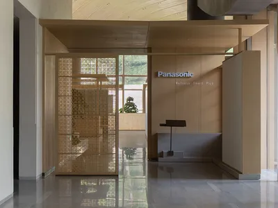 現代日式玄關大廳，特色為戲劇性曲線木質天花板、木格柵屏風、拋光混凝土地面，以及Panasonic健康智慧展示區。