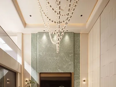 奢華現代餐廳，設有大型圓形大理石餐桌、十張米 beige 軟墊扶手椅、巨型層疊水晶吊燈、鼠尾草綠大理石主牆與壁爐，以及黑米色圖案地毯。
