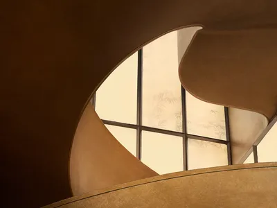 Close-up view of a sculptural bronze spiral staircase featuring smooth curved forms and traditional Chinese cloud and mountain embossed patterns.