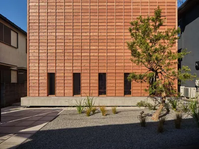 現代兩層樓住宅外牆全部使用水平杉木板材，建築坐落於混凝土基座上，前方設有日式碎石庭園與修剪過的松樹。