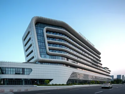 Exterior view of the Grand Intercontinental Hotel in Taichung, Taiwan, showcasing its distinctive curved white facade and extensive glass windows under a clear blue sky.