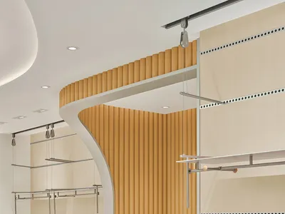 Modern minimalist boutique interior featuring a curved white reception desk, vertical oak slat wall, and floating metal clothing racks under bright recessed lighting.