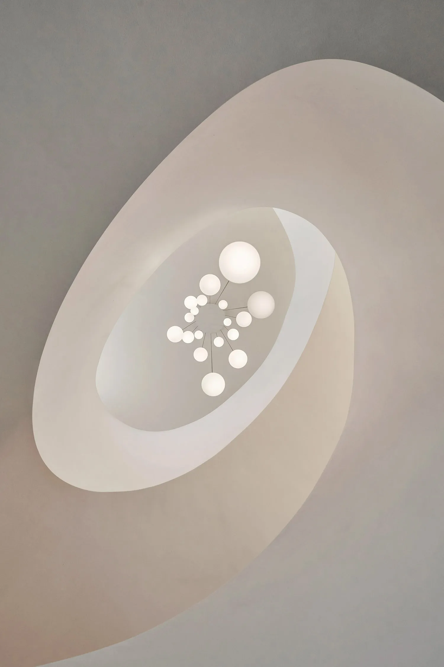 Minimalist ceiling fixture with spherical lights arranged in a flower-like pattern, featuring a light-colored, smooth, curved