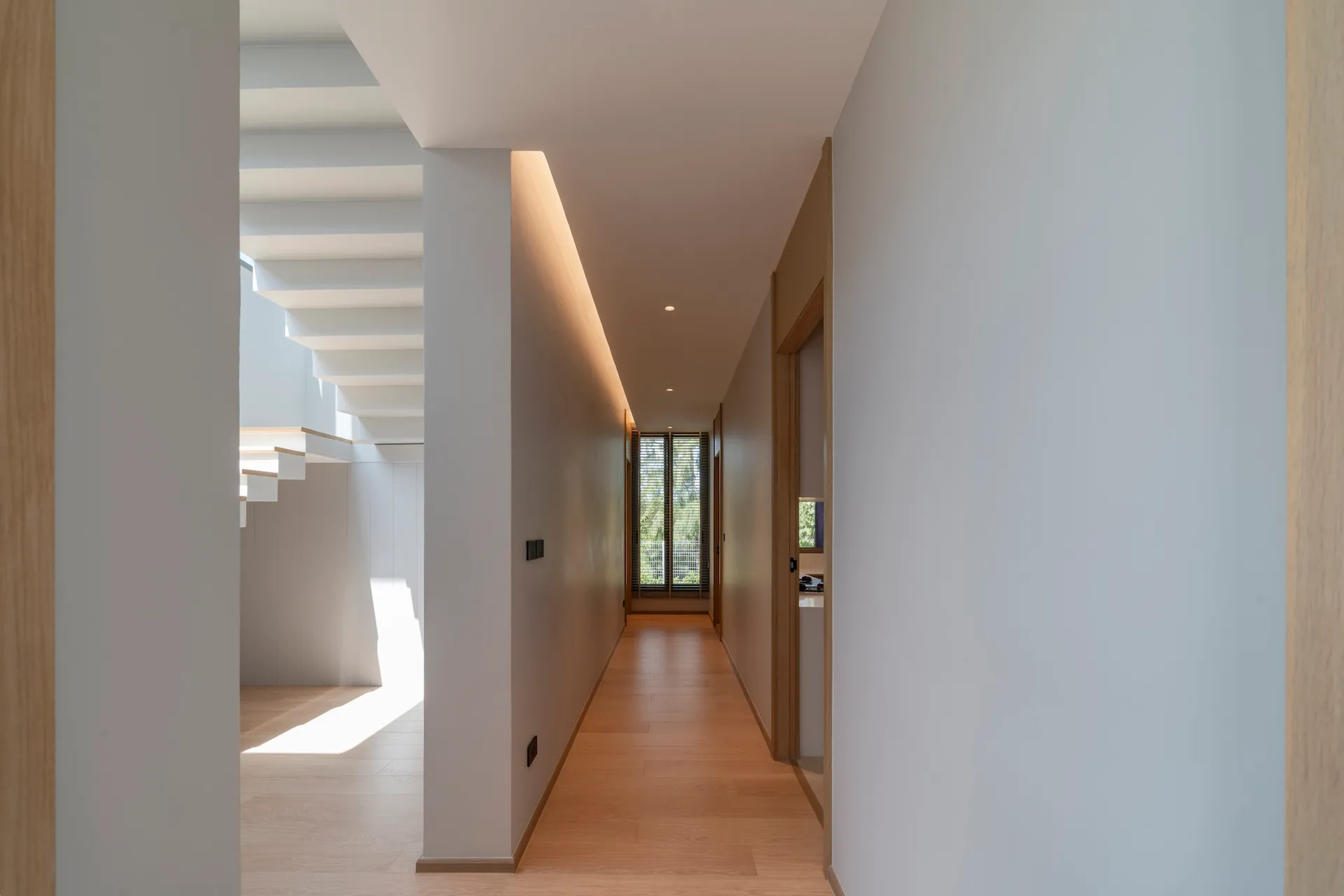 A modern minimalist hallway with wooden floors and white walls