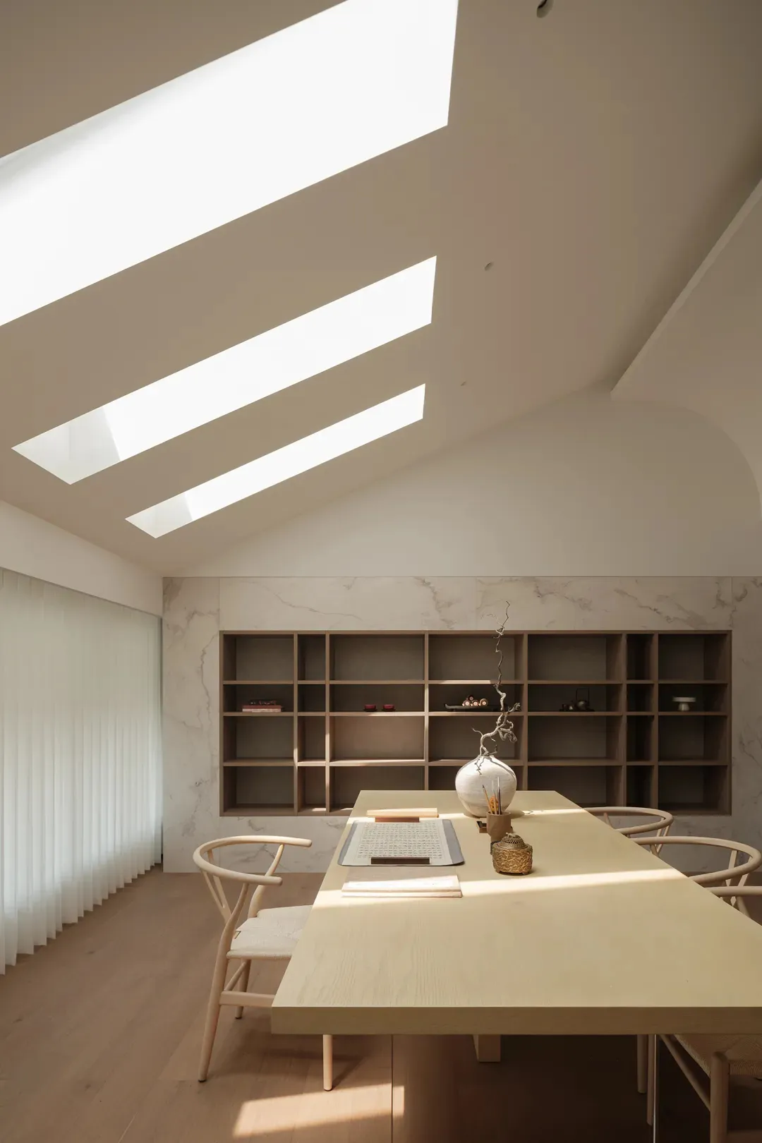 Contemporary study with wooden table, marble accent wall, and skylights