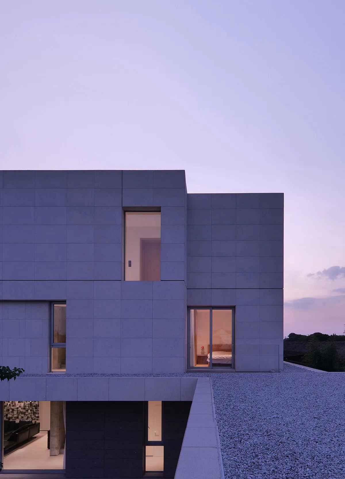 A minimalist house with concrete exterior materials and large windows.