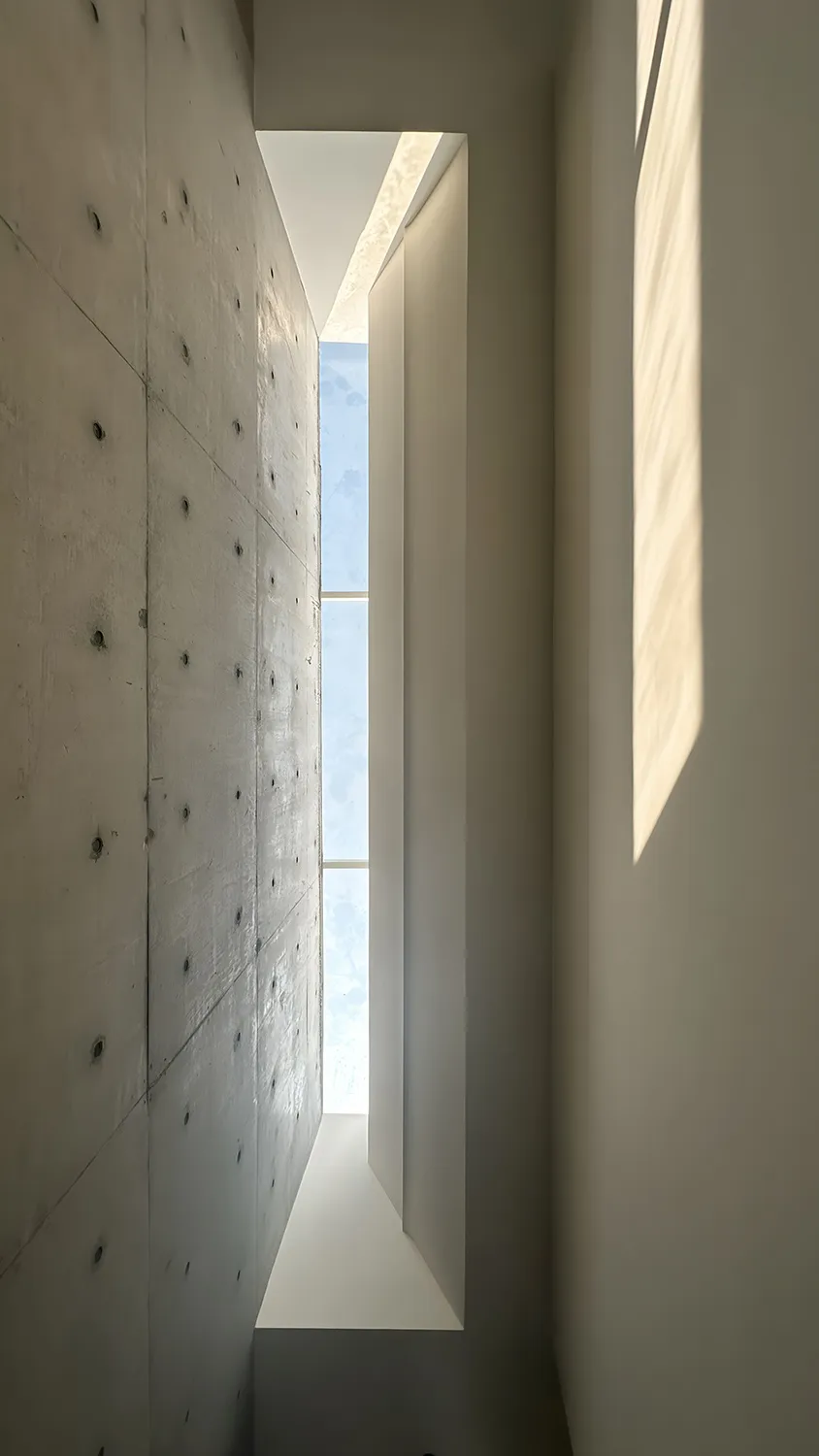 Modern minimalist architecture featuring concrete and glass elements with a large window.