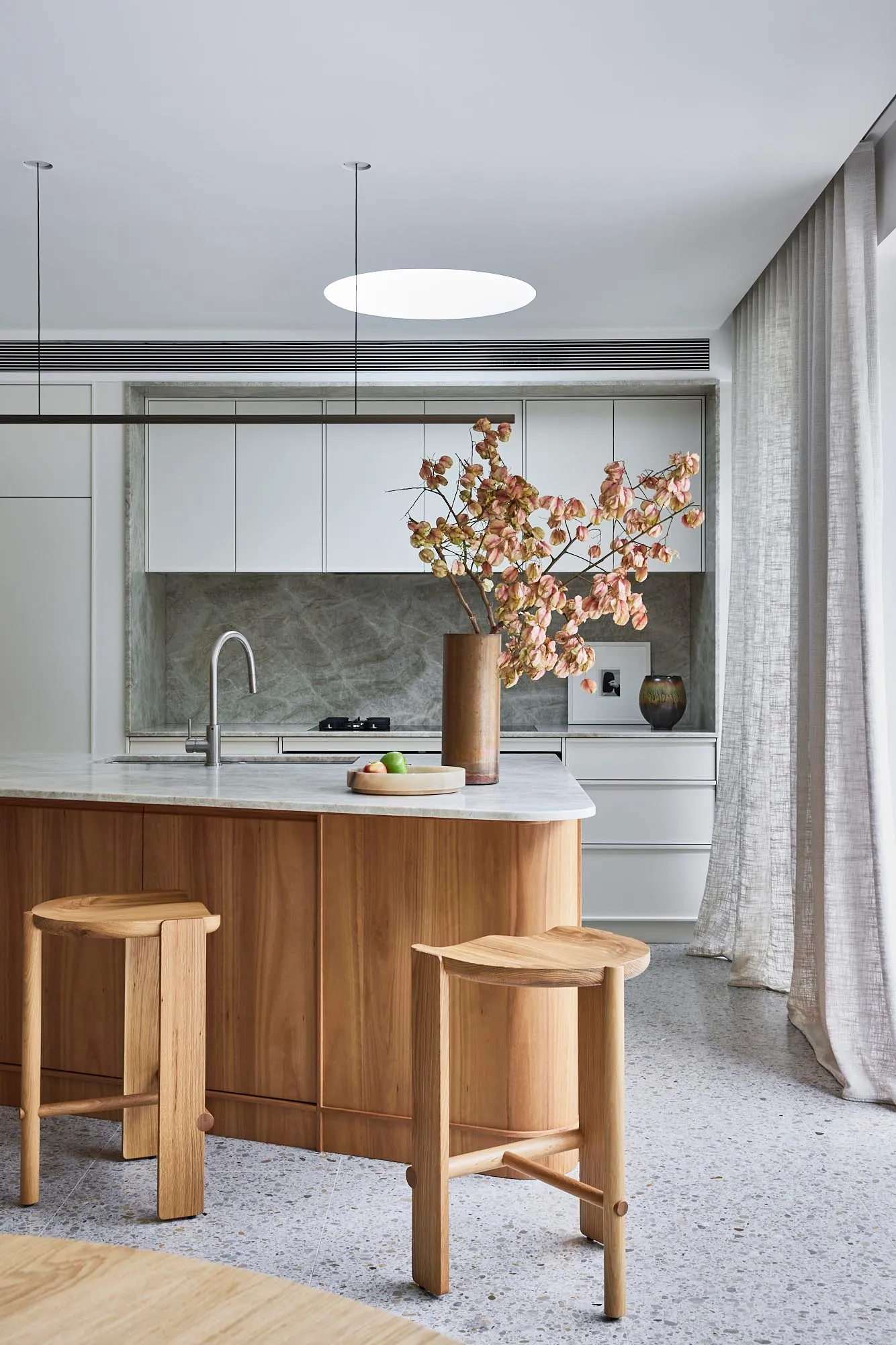 A modern kitchen featuring marble countertops and wood accents, with a minimalist design aesthetic.