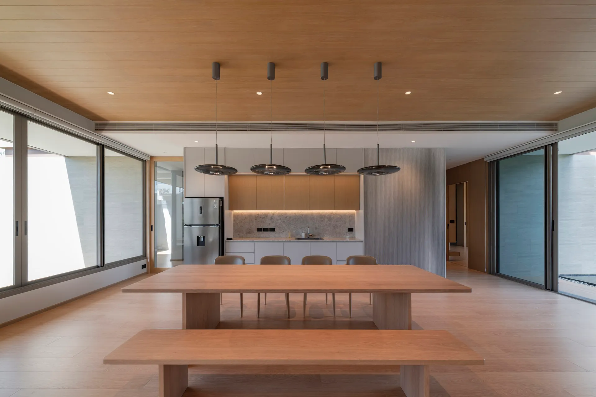 Modern minimalist residential kitchen featuring marble countertops and wood finishes.