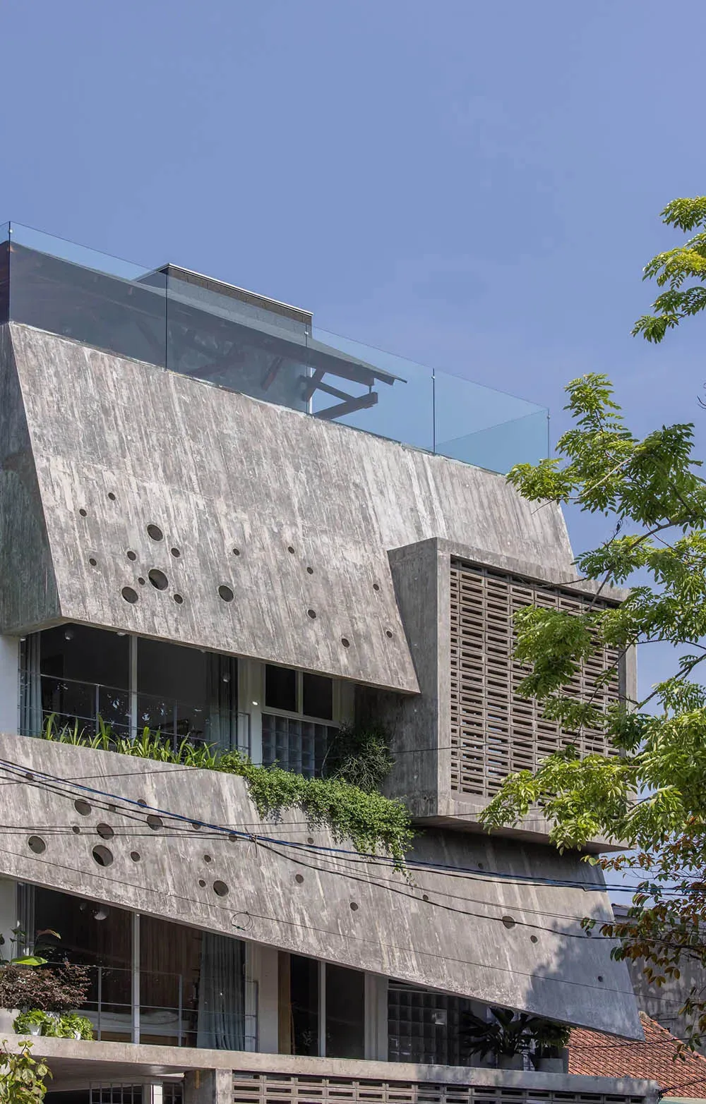 A modern building with a concrete façade featuring circular patterns and a glass rooftop.