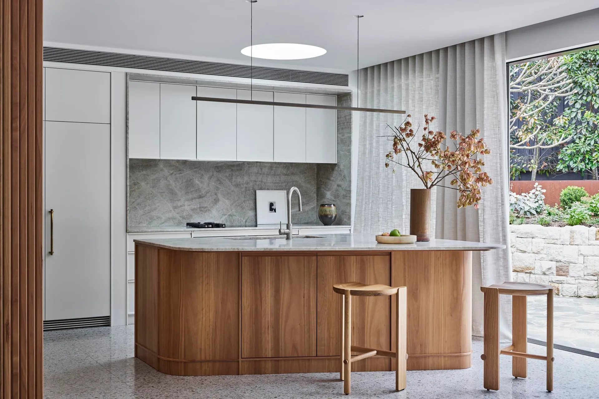 A modern kitchen with wooden cabinets and a marble countertop.