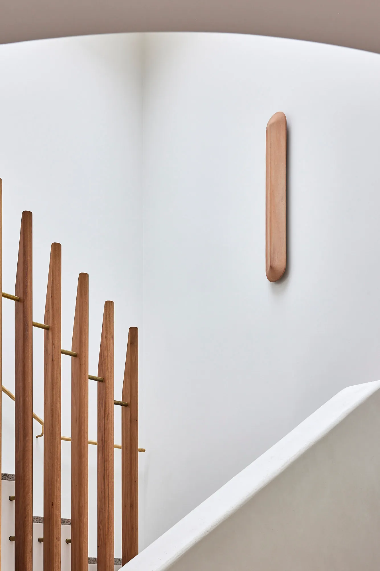 A minimalist interior design featuring a wooden staircase with a white railing.