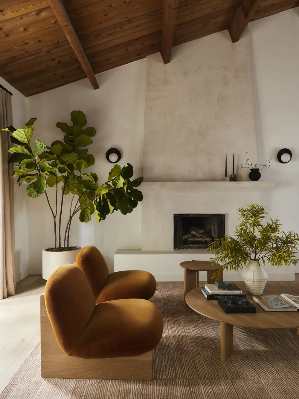 Modern living room with orange upholstered chairs, wooden coffee table, green potted plant, and fireplace.