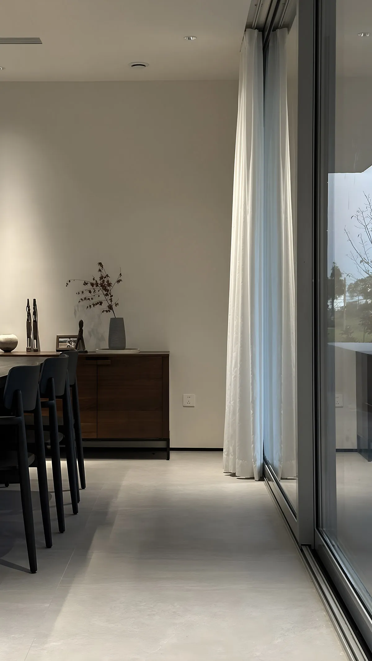 Modern minimalist residential interior with white curtains and wooden cabinet.