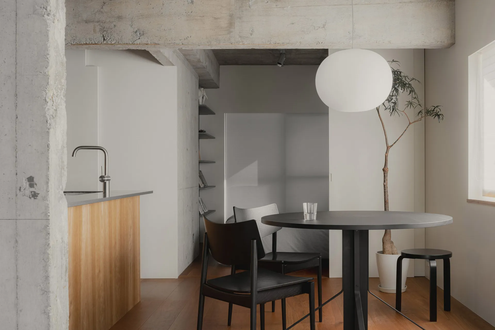 Modern minimalist living room with a concrete floor and minimalist decor, featuring a round dining table and chairs, and a mi