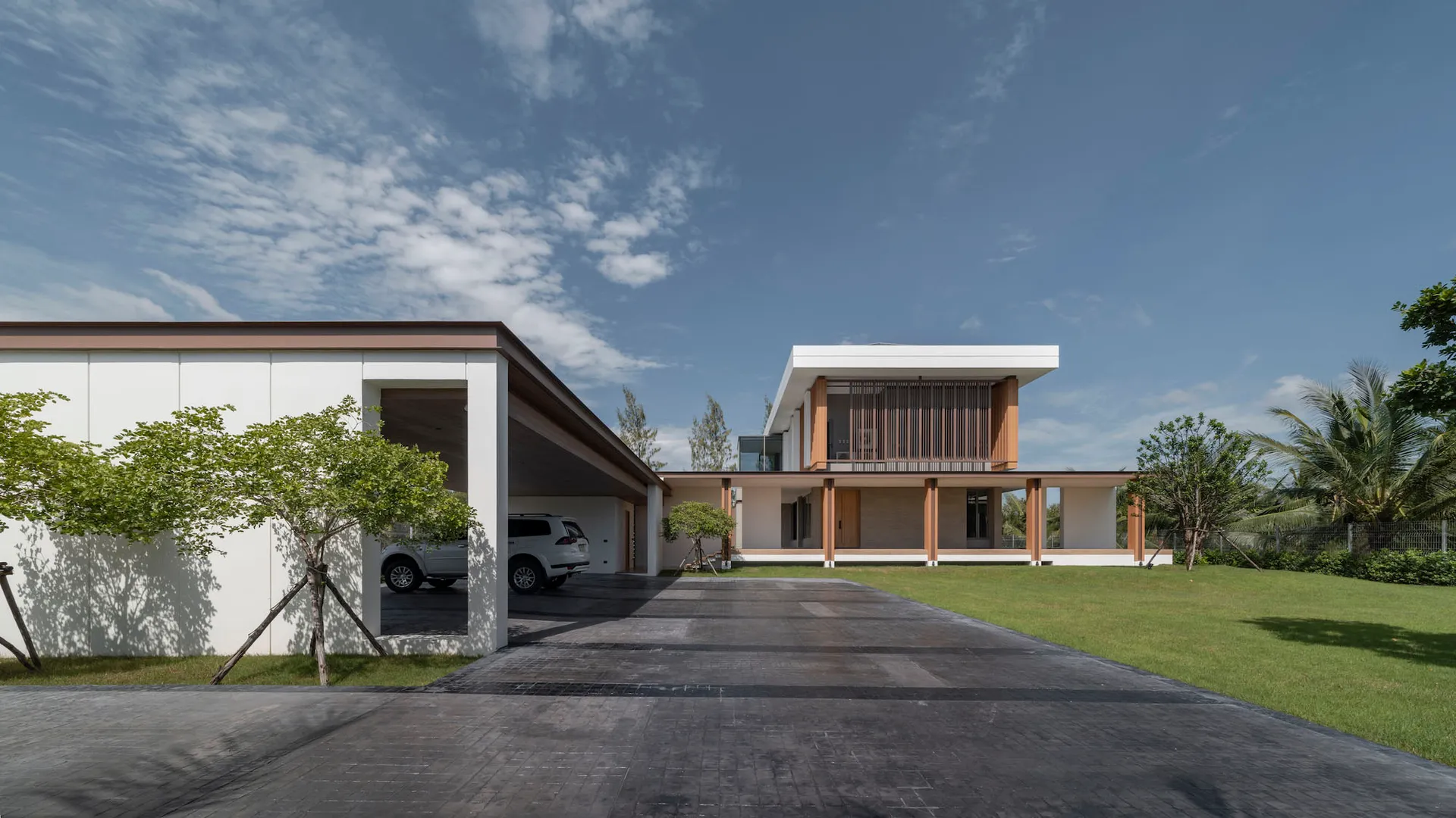 A modern residential exterior with a concrete facade and large driveway.