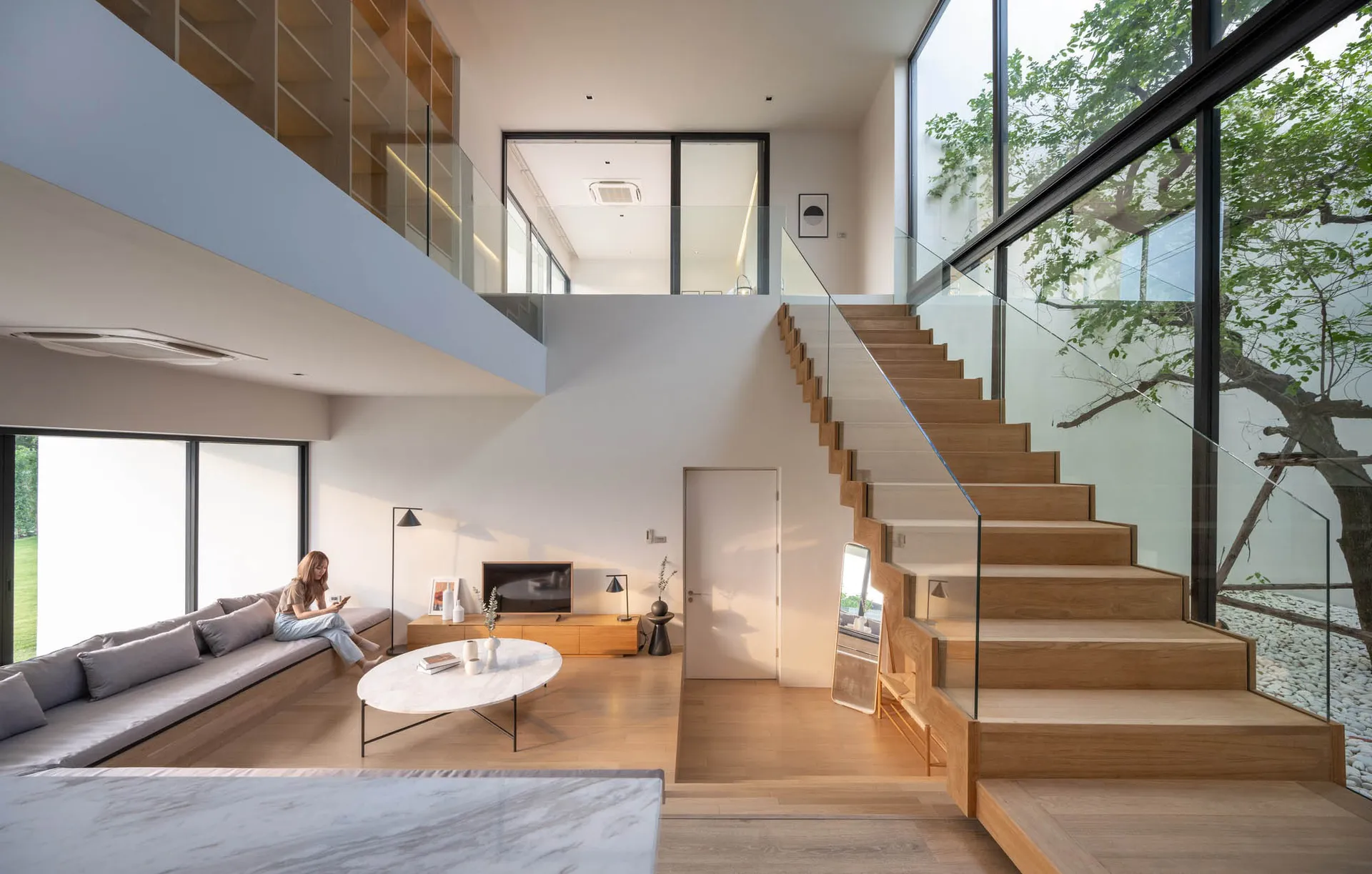 A modern, minimalist residential staircase with wooden steps and glass railings.
