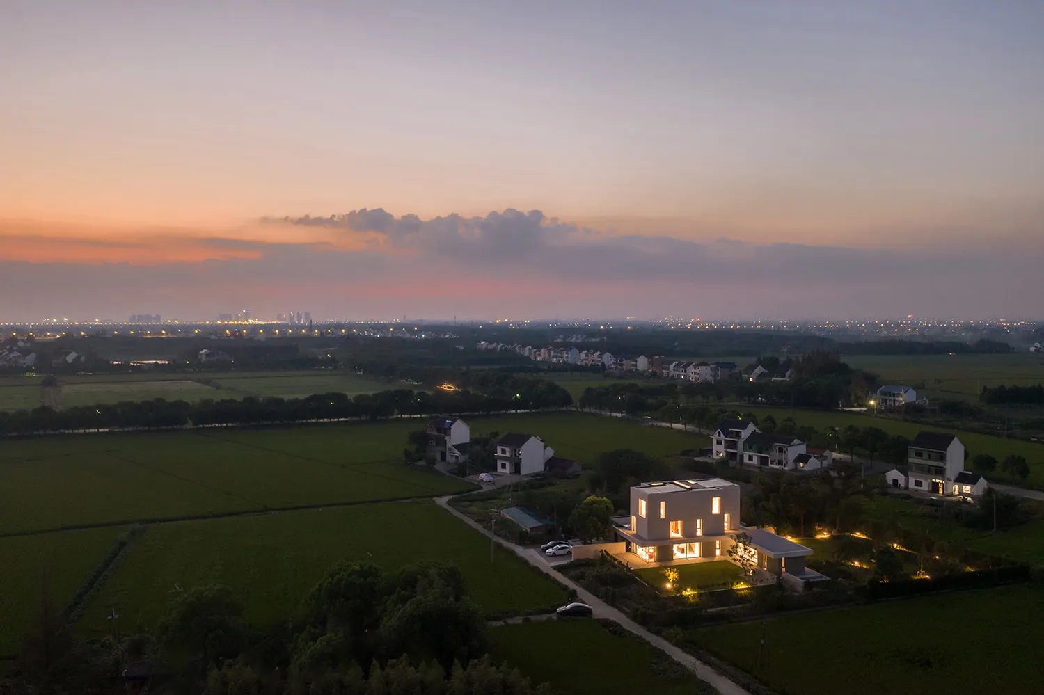 俯瞰鄉村生活空間,現代建築與夕陽天空為背景。
