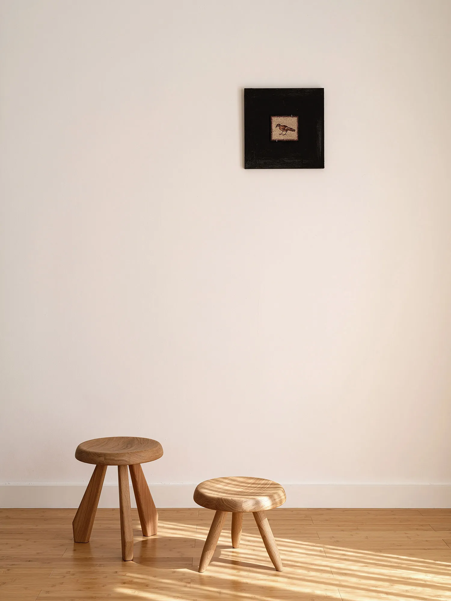 A minimalist wooden stool with three legs in a Scandinavian style setting.