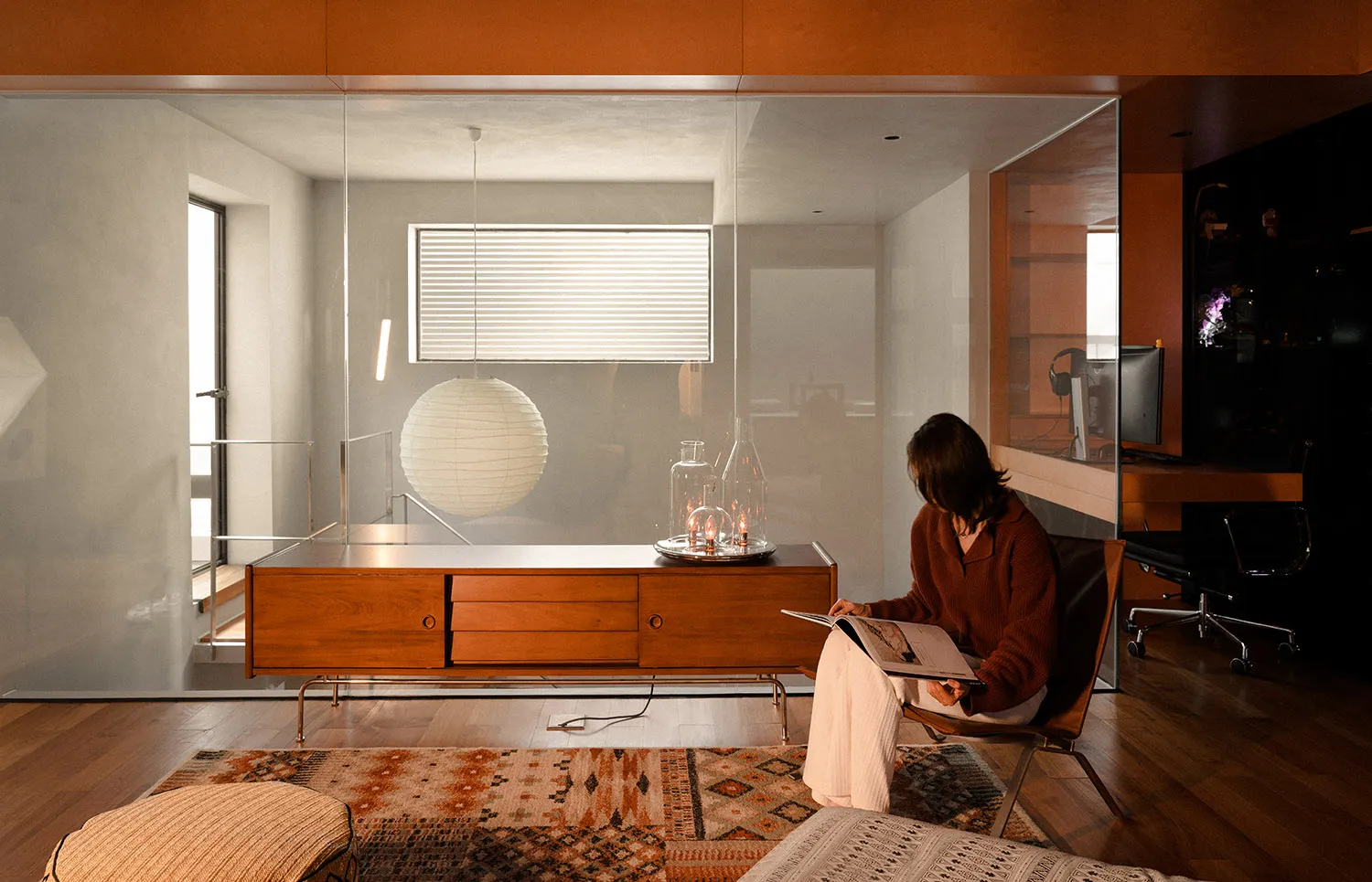A modern living room with wood flooring, glass coffee table, and fabric seating.