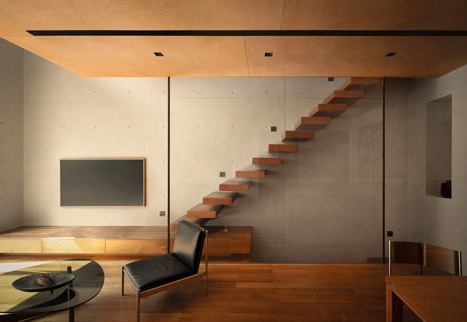 Modern living space with a wooden staircase and a glass wall.