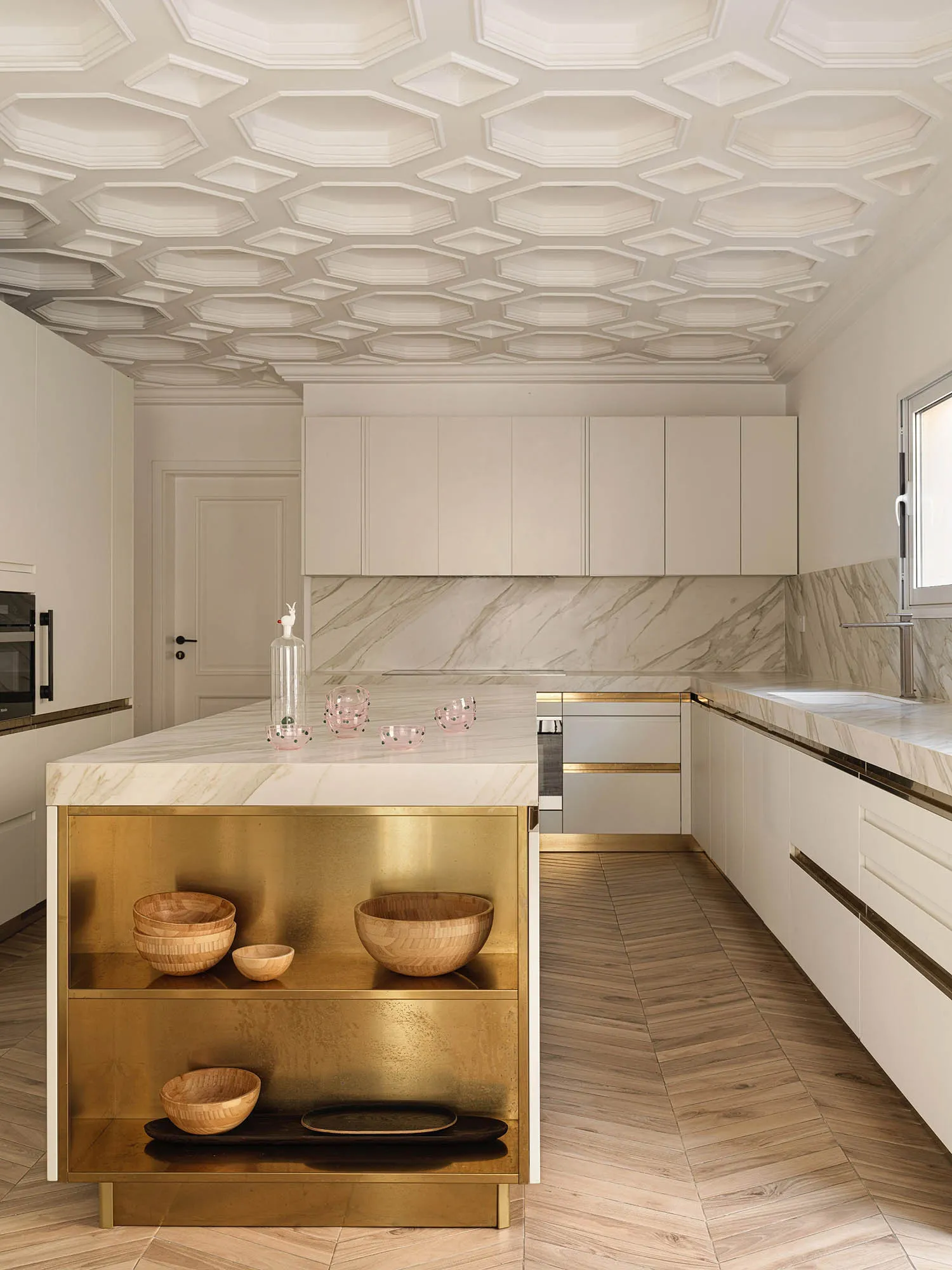 Contemporary kitchen featuring marble countertops and brass accents