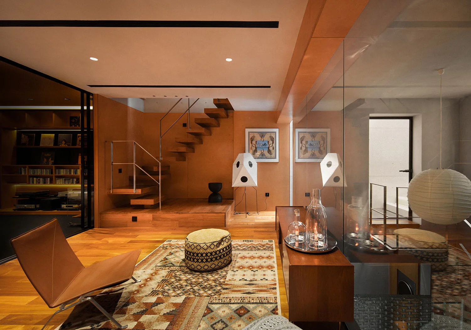 A modern minimalist living room featuring wooden flooring and furniture, with a cozy atmosphere created by comfortable seatin