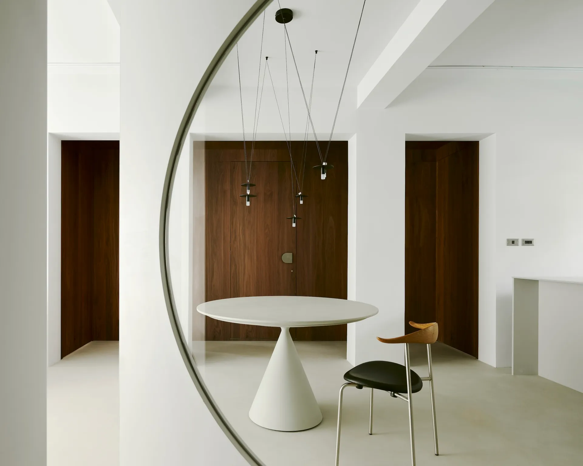 Modern white dining room with concrete floor, minimalist design, and aconic table.