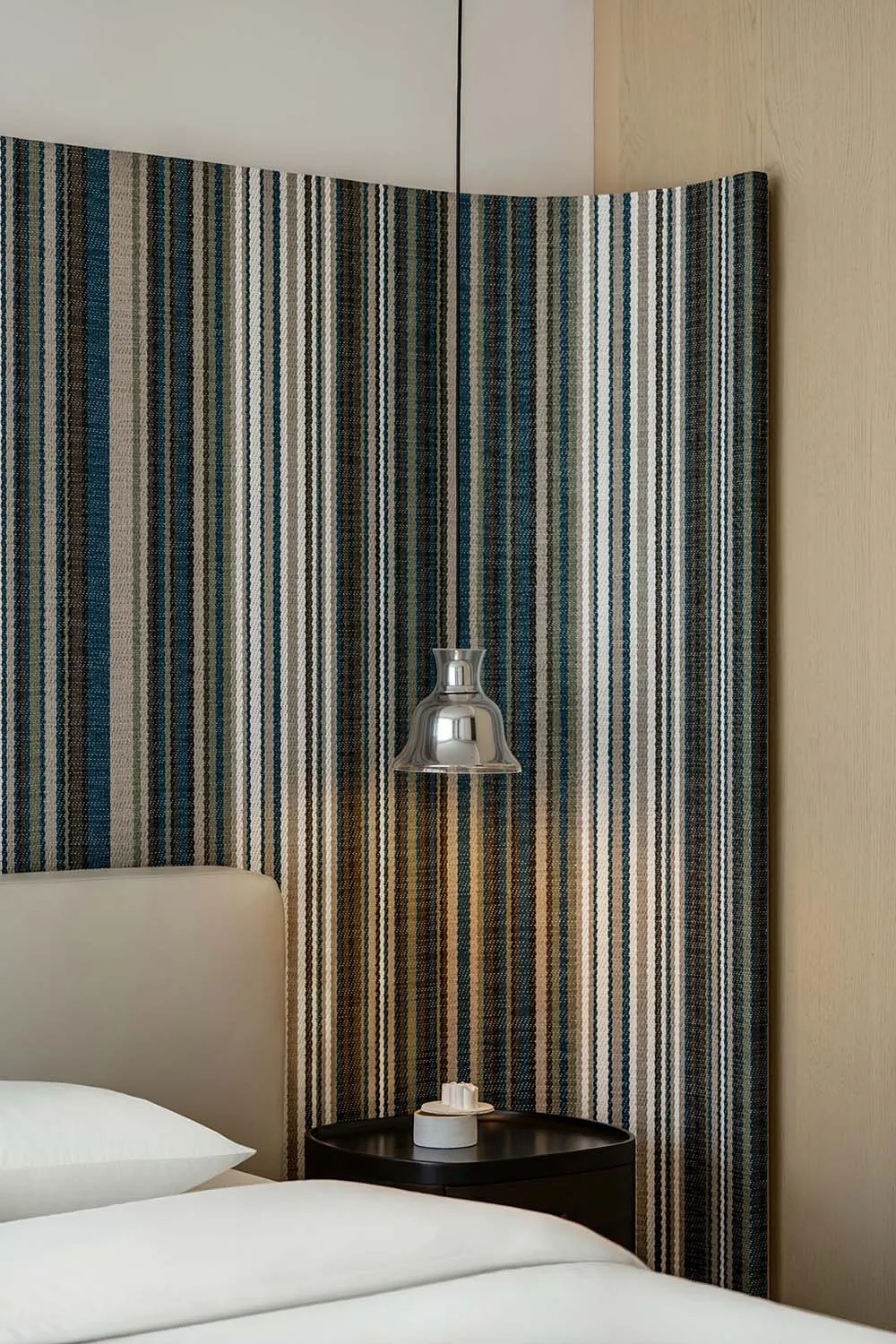 Modern minimalist bedroom featuring a striped fabric panel on the headboard, creating a stylish and sleek design.