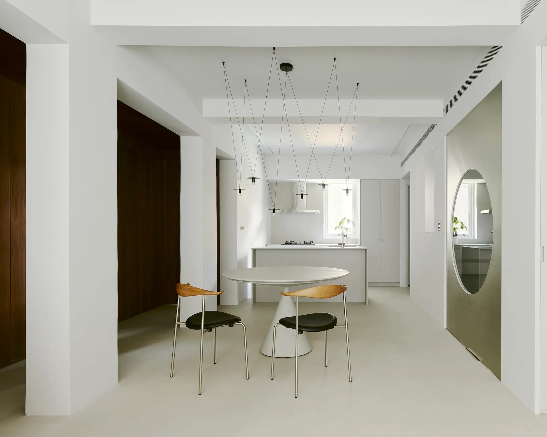 Modern kitchen with white concrete flooring, minimalist dining area, and sleek, clean lines.