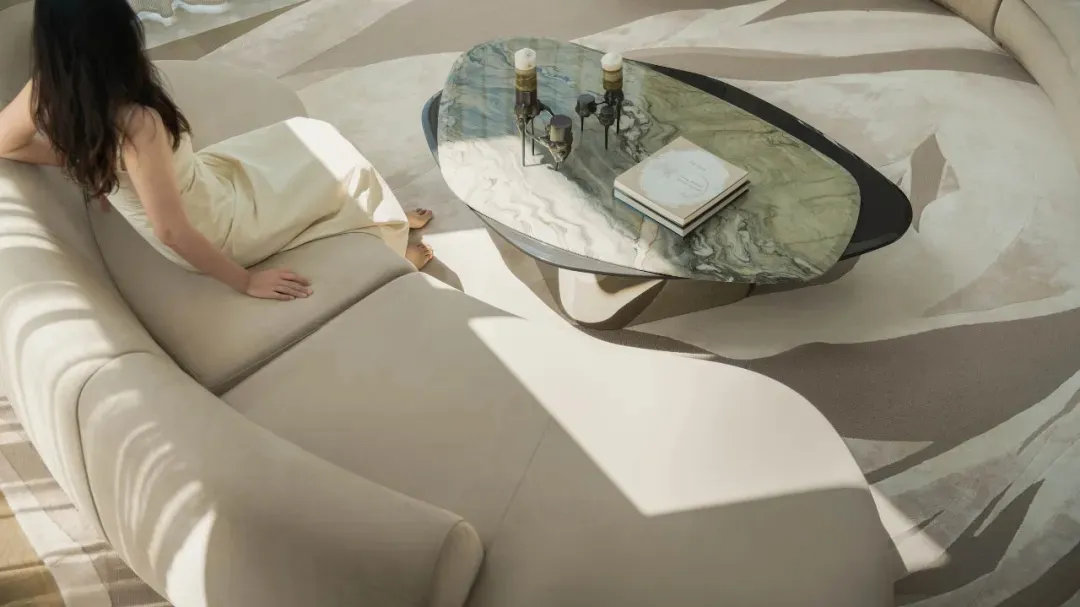 A modern living room featuring marble coffee table and leather sofa, with sunlight streaming through the window.