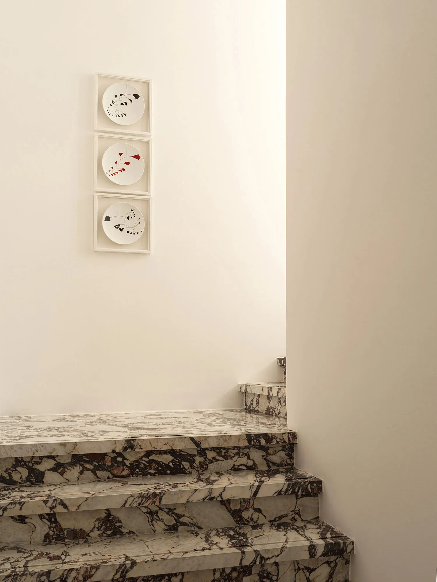 Modern staircase with marble steps and a wall art display.