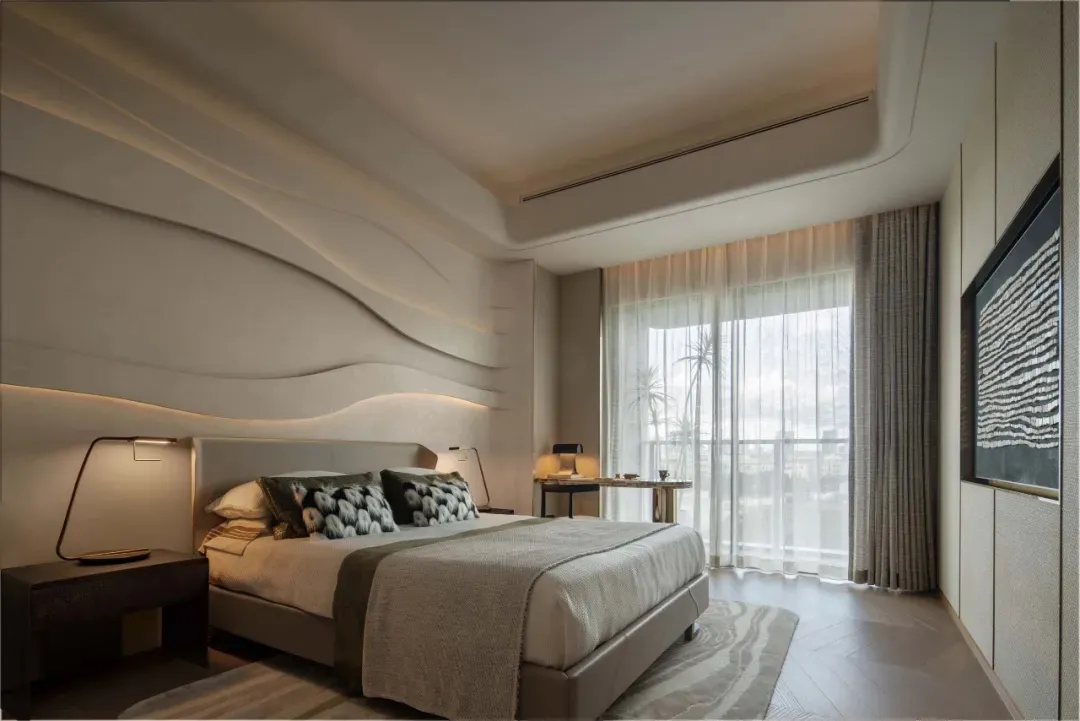 Modern minimalist bedroom with a king-sized bed, wave-patterned headboard, and glass curtains allowing natural light to flood