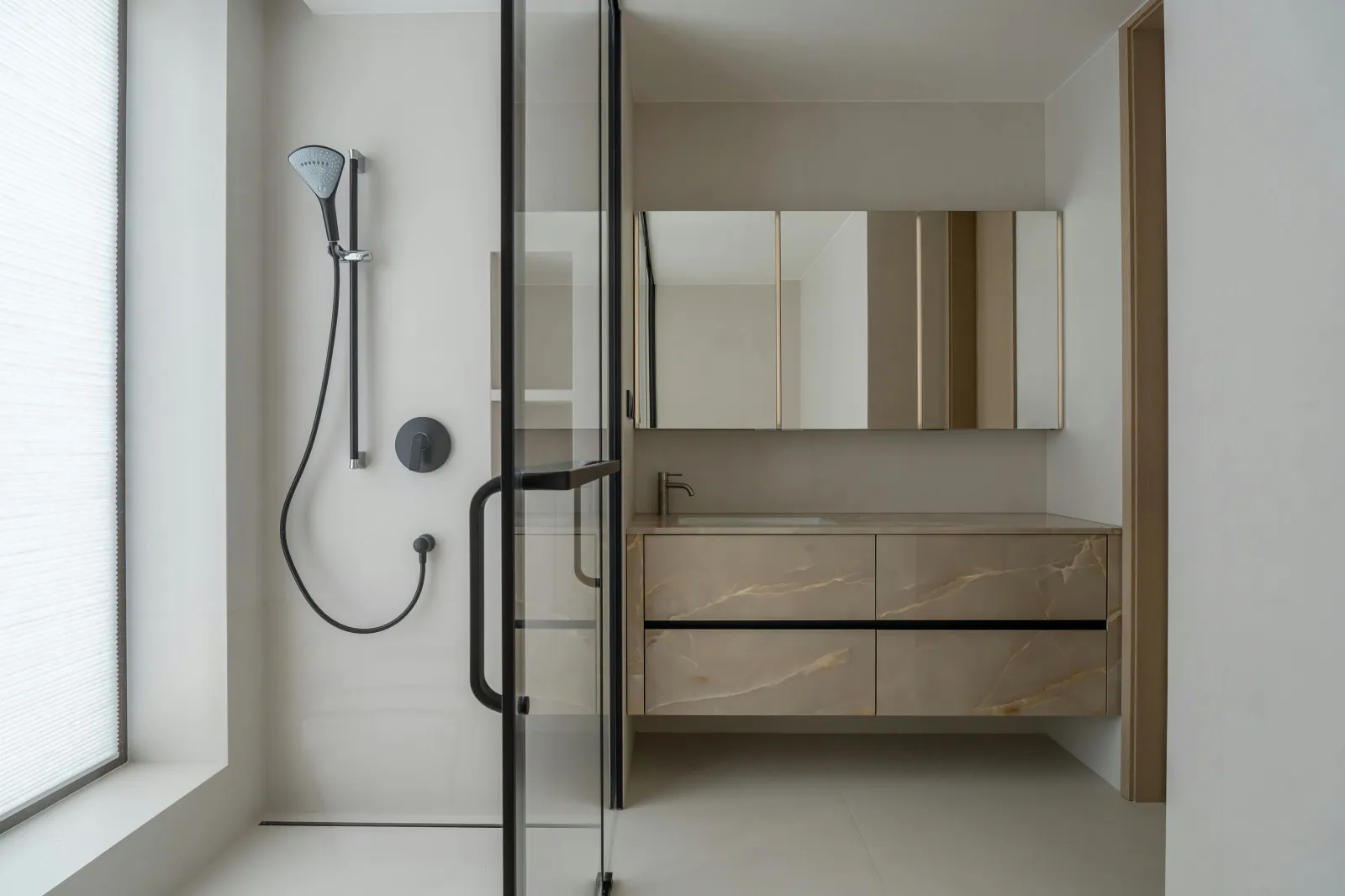 Modern minimalist bathroom featuring a marble countertop and vanity, glass walk-in shower enclosure, and a large mirror above