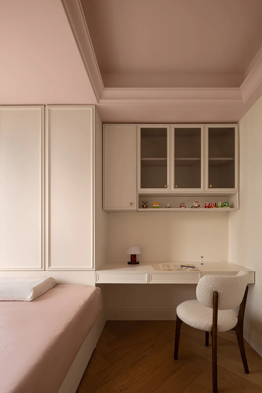 Minimalist bedroom with pink bedding and a wooden desk.