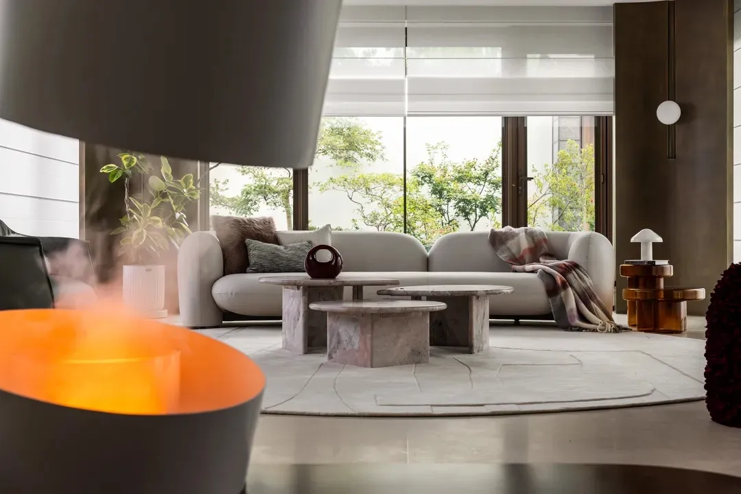 Contemporary living room with white sofa, coffee tables, and a cozy blanket on the couch.